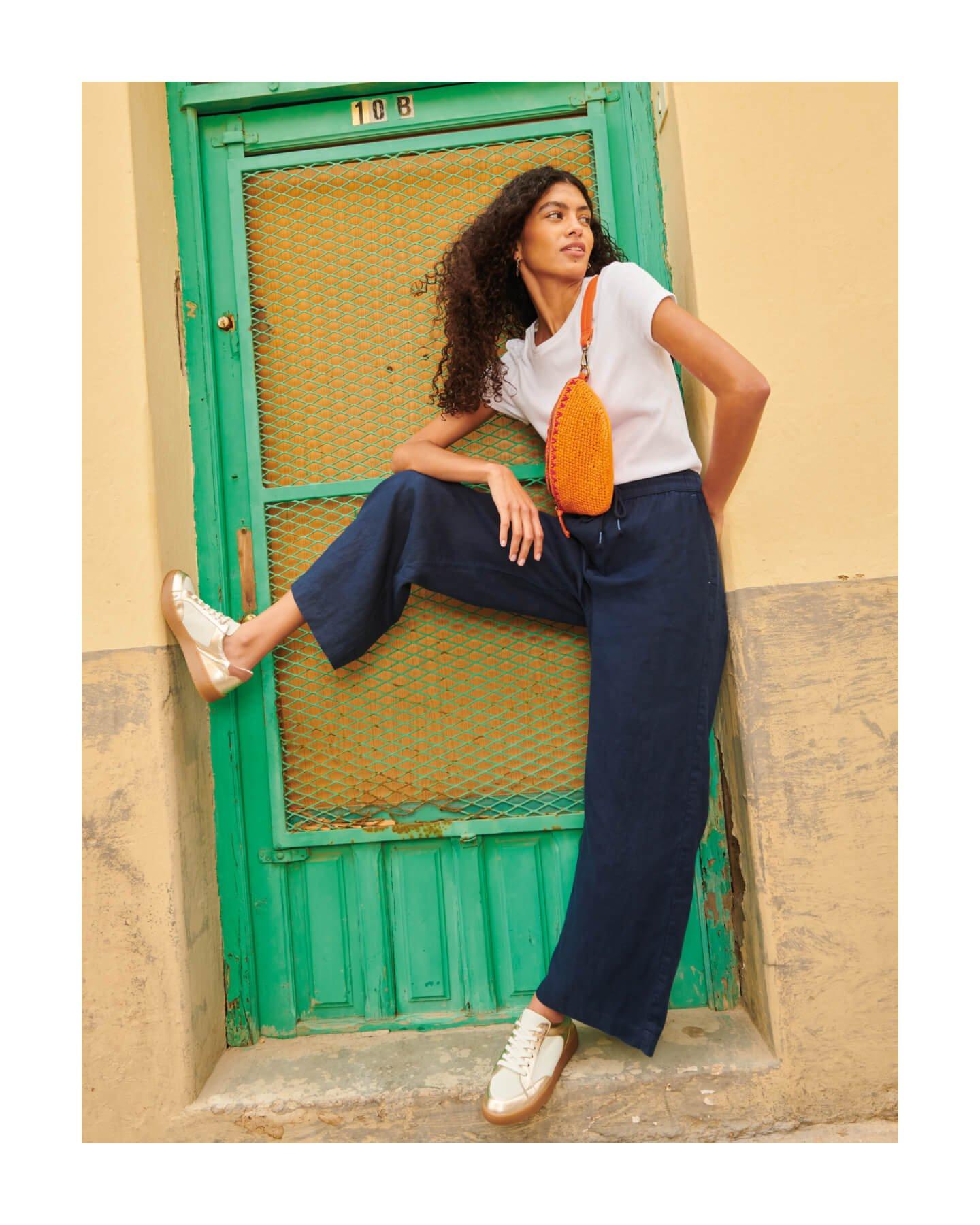 Woman wearing linen trousers leaning in doorway